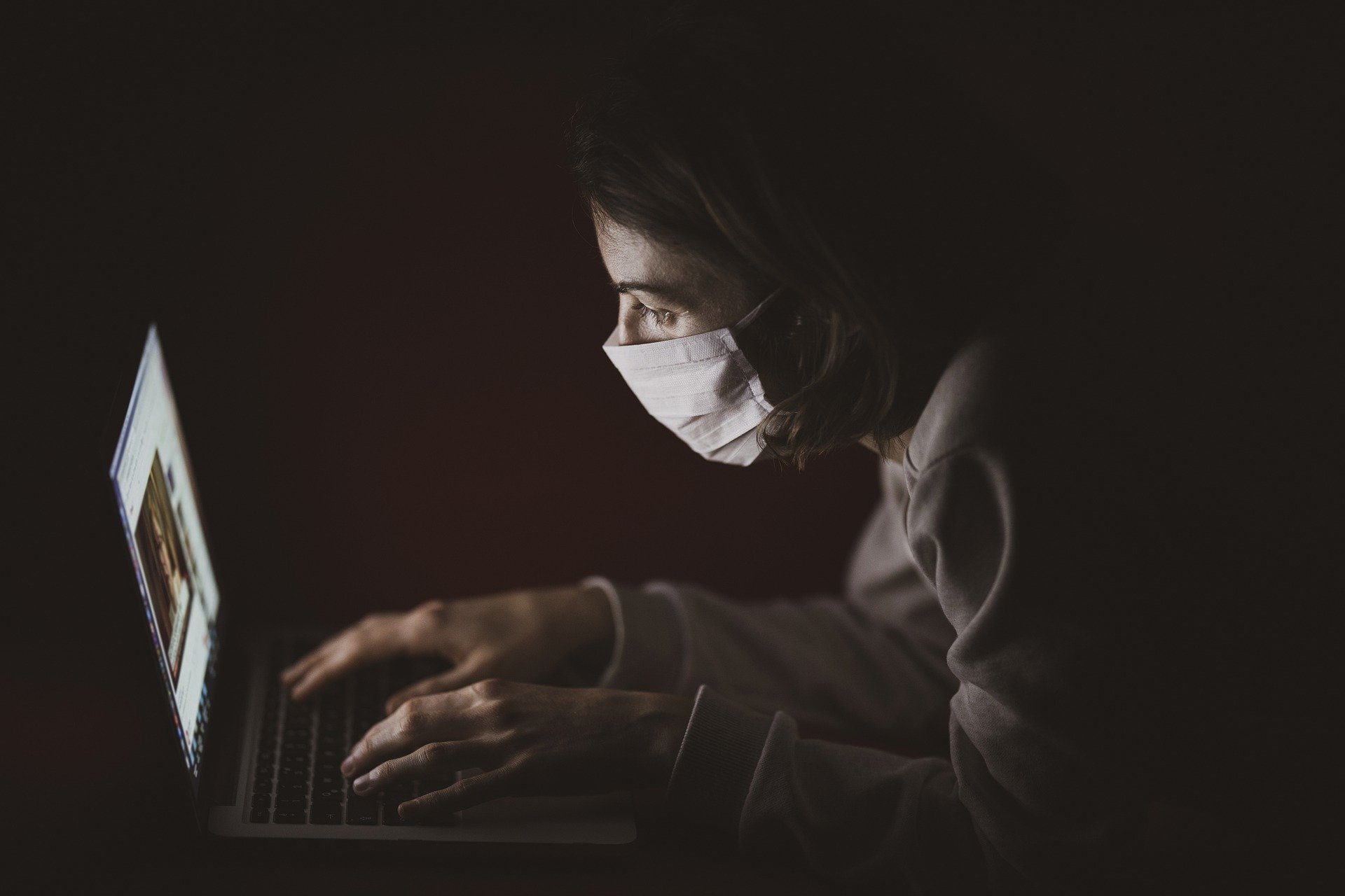 masked person using laptop