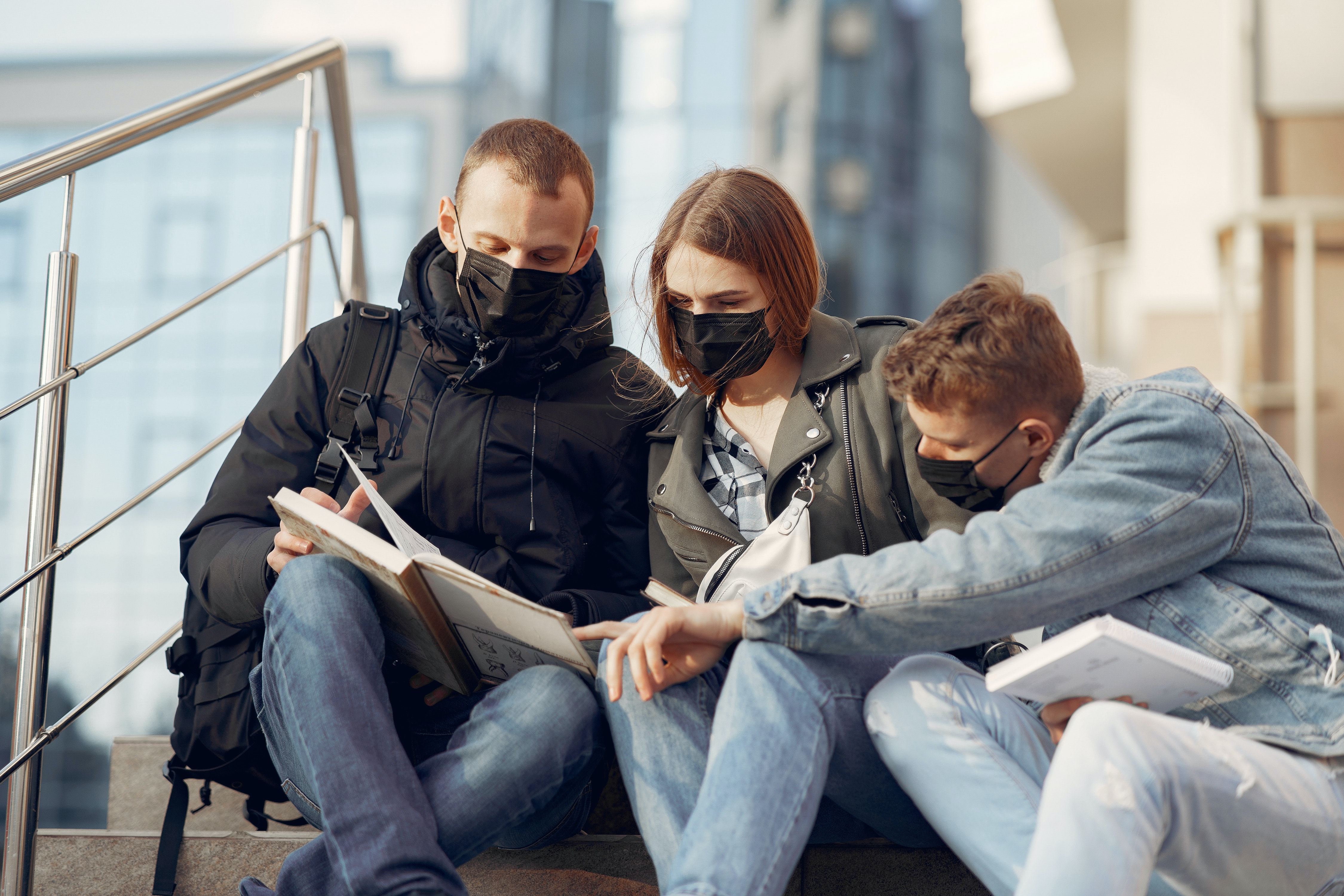 three masked students studying together
