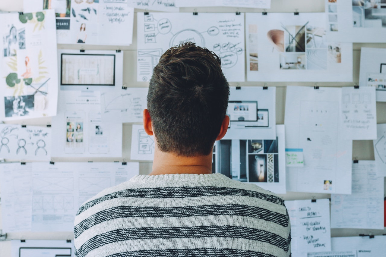 Man looking at whiteboard covered in notes