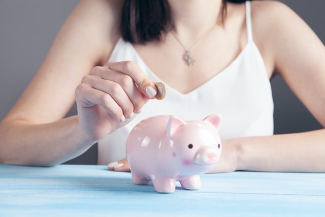 woman depositing coin in piggy bank