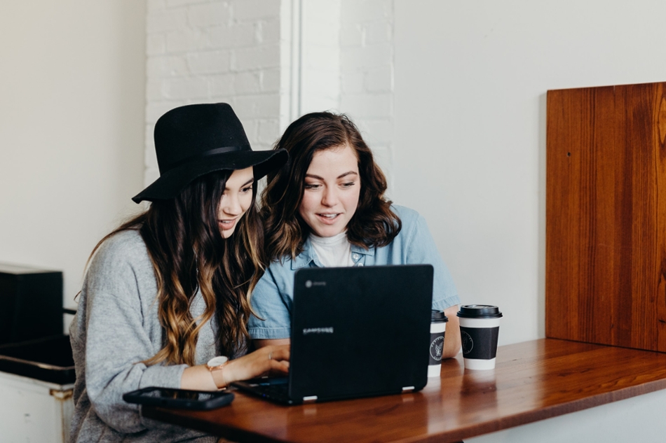 women looking at a laptop screen and smiling