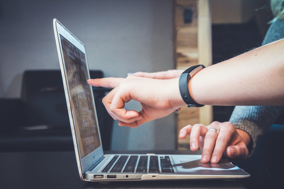 hands pointing at the screen of a computer